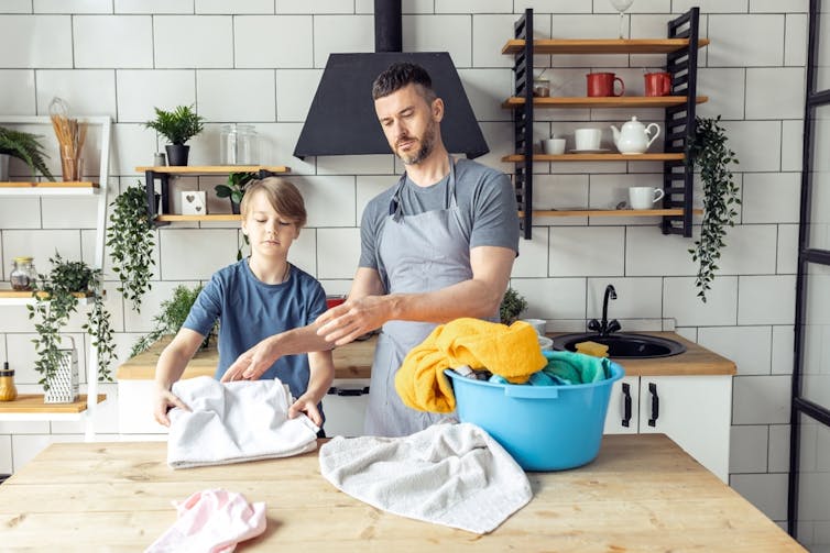 A man and child sort laundry together.