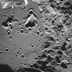 A grayscale image of a surface with lots of darker pockmarks
