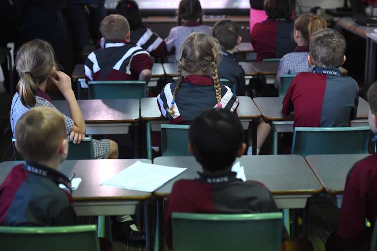Children sitting at desks, facing the front of the classroom.
