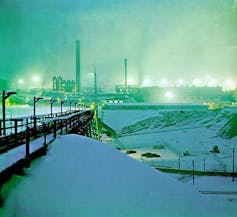 A large industrial complex lit up against snow.