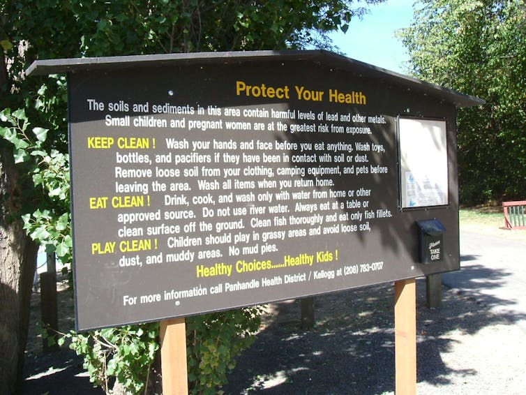 A photo of a large sign with warnings about soils and sediments containing harmful levels of lead.