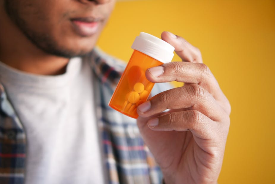 A man holds a bottle of prescription pills.