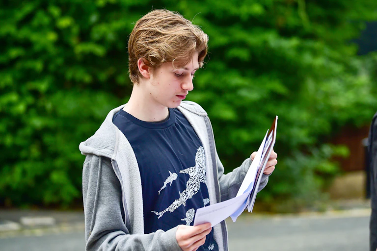 Teenage boy looking at exam results outside