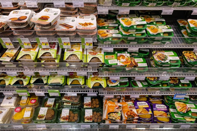 Shop shelves with rows of different packaged alternative meat products.