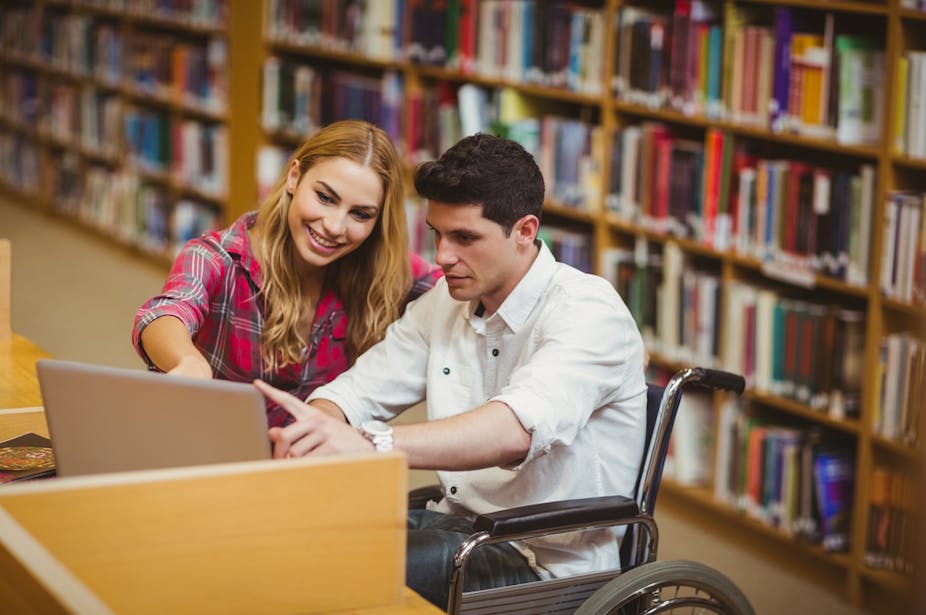 Deux étudiants consultent un écran d'ordinateur dans une bibliothèque universitaire