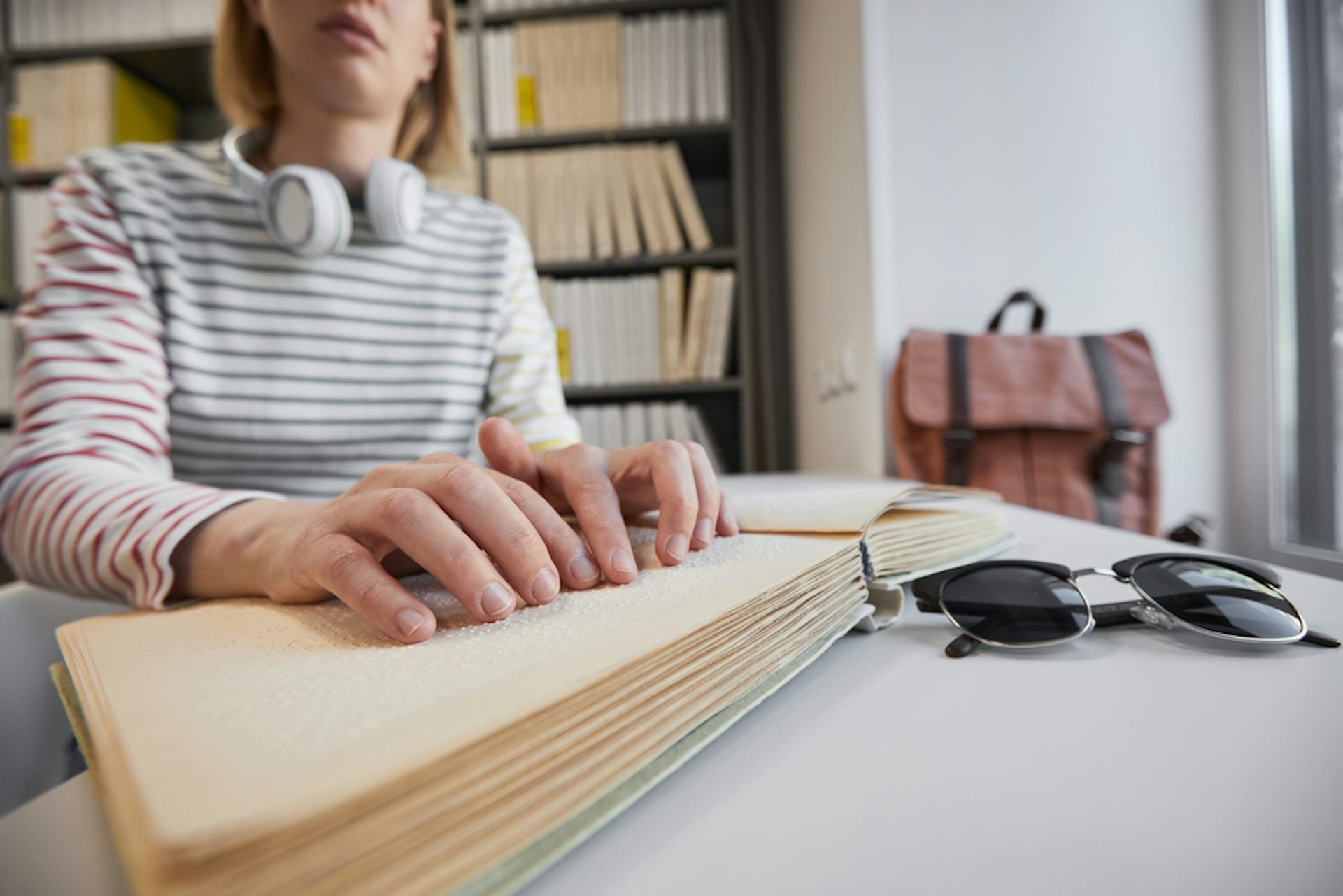 Une étudiante lit un livre en braille à la bibliothèque universitaire
