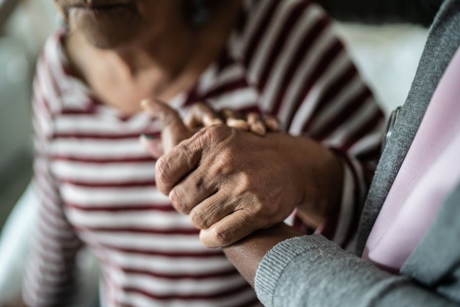 Close-up of caregiver holding the hand of an older adult