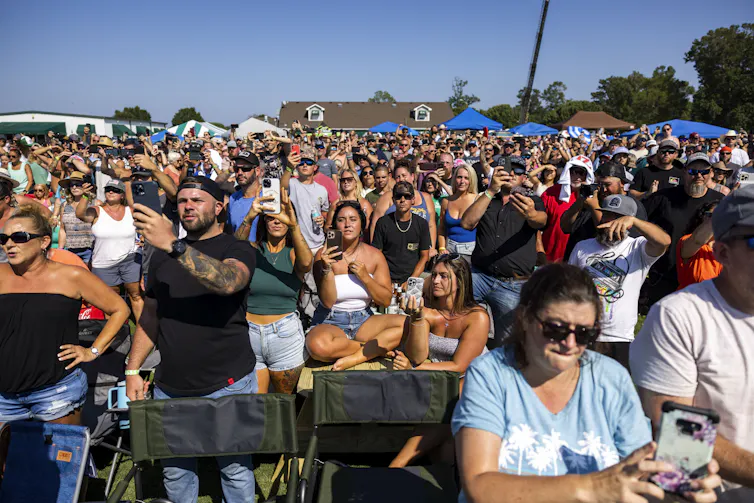 Une foule en tenue estivale assiste à un concert en plein air