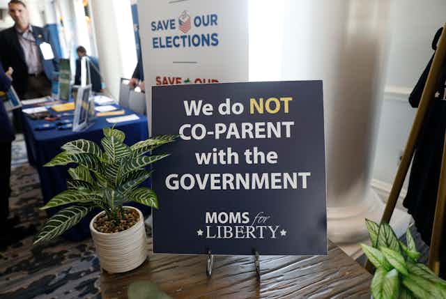 A sign that says 'We do not co-parent with the government' and 'MOMS for LIBERTY'