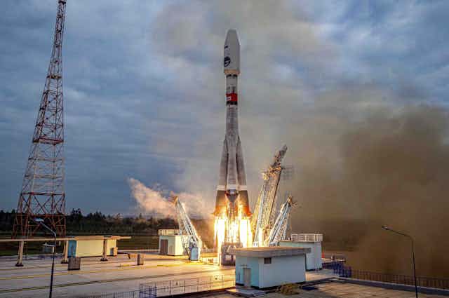 A photo shows a rocket firing its engines on the launch pad.