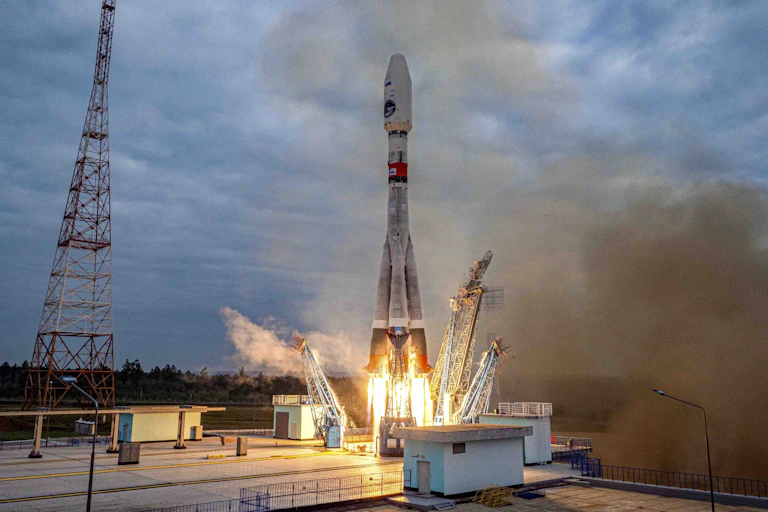 A photo shows a rocket firing its engines on the launch pad.