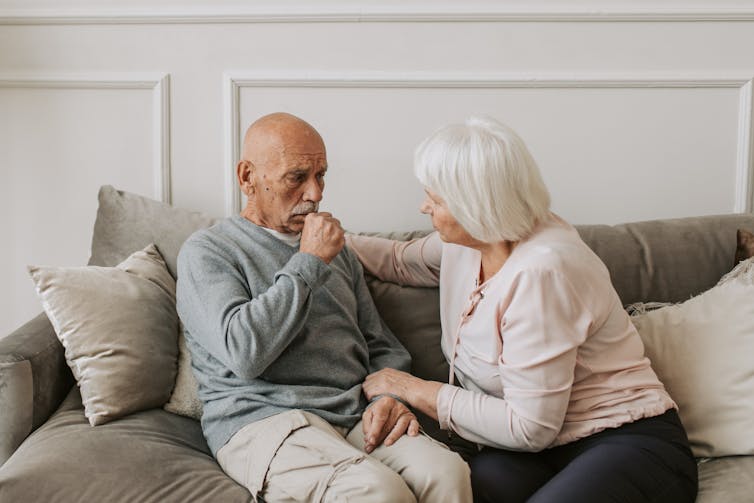 Older man coughs, while his partner looks concerned