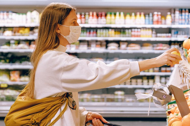 Woman at supermarket reaches for an orange