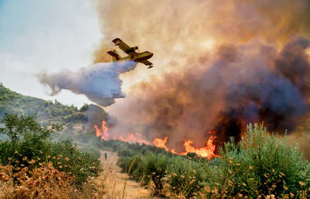 Avión libera agua sobre las llamas de un incendio.