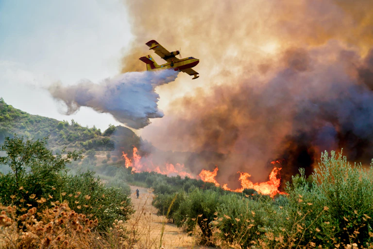 Avión libera agua sobre las llamas de un incendio.