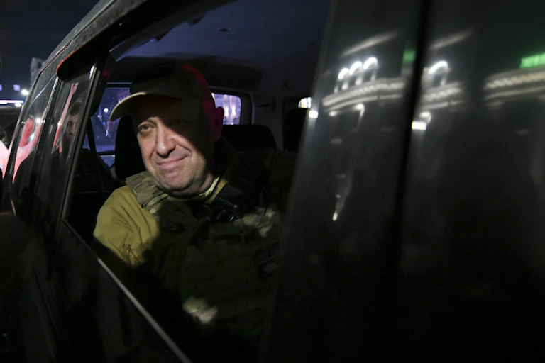 Un hombre vestido de militar mira por la ventanilla de un coche mientras viaja en el asiento trasero.