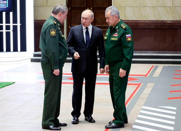 Vladimir Putin speaks with the Russian chief of general staff Valery Gerasimov (left) and defence minister Sergei Shoigu (right).