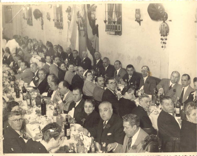 Fotografía de un comedor con mesas largas corridas llenas de gente.