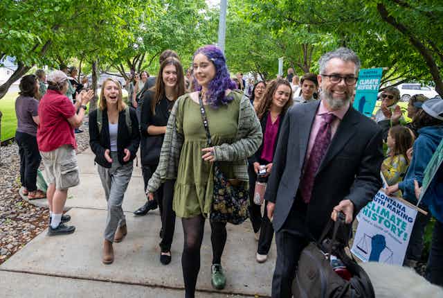Young people laugh as they walk with their lawyer.