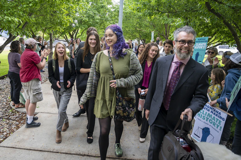 Young people laugh as they walk with their lawyer.