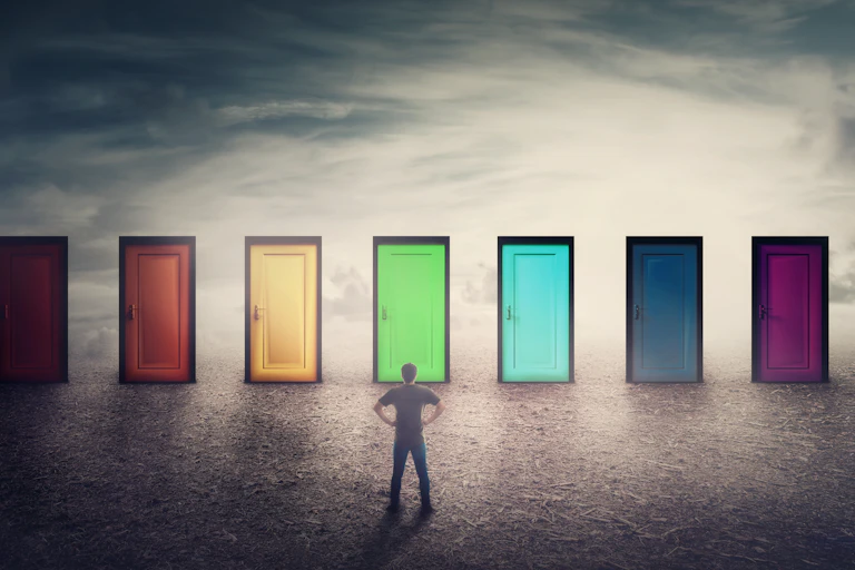 Man stands in front of various coloured doorways.