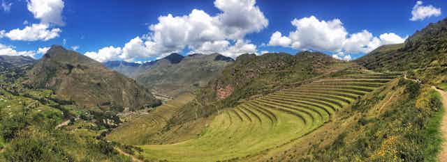 Paisaje peruano de montañas con escaleras de hierba y grandes montañas al final.