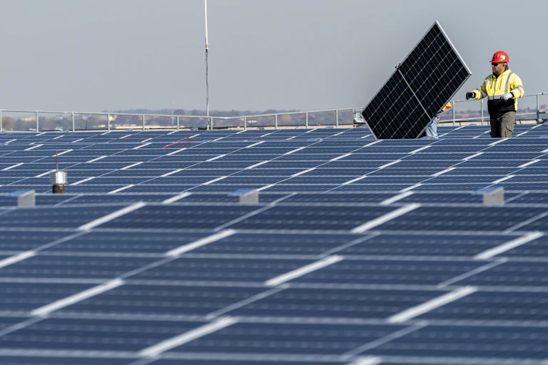 A construction worker installs a solar panel on a huge roof