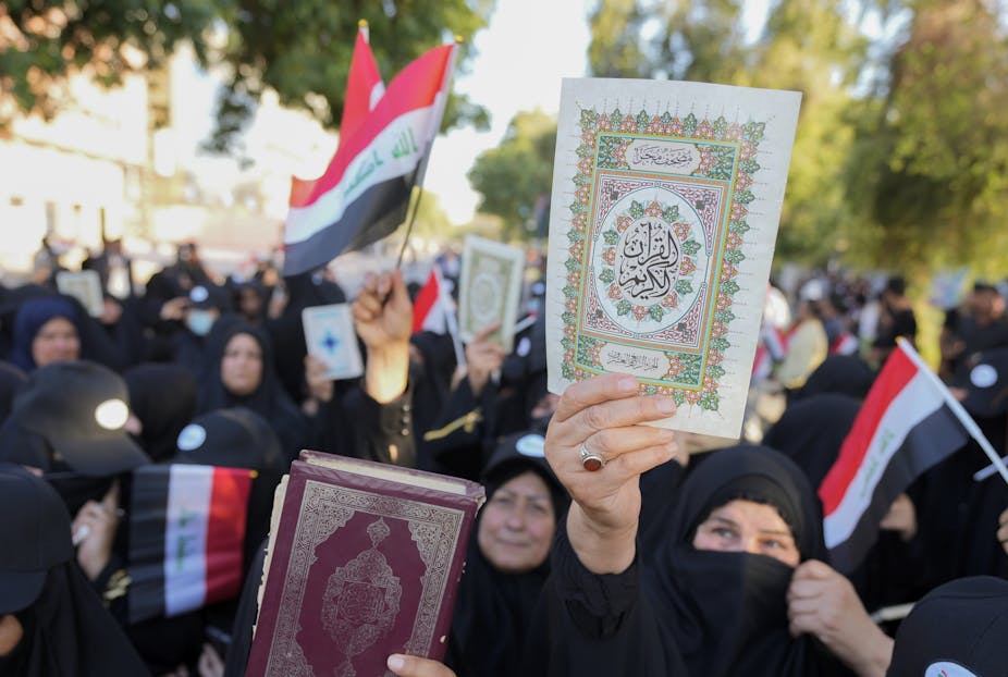 Women wearing the abaya hold up copies us the Quran during a protest.