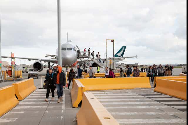 Passengers disembarking from a plane at the airport