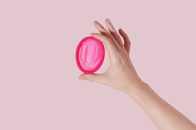 hand holds pink menstrual disc
