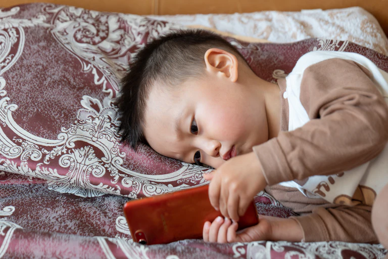 Boy on bed looking at phone