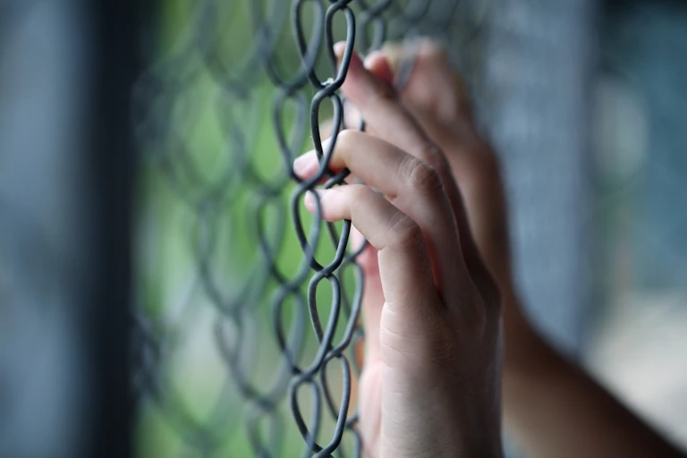 Hands at wire fence