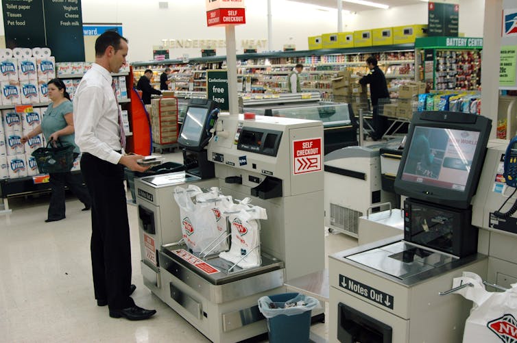 A man on his own serves himself at a supermarket checkout