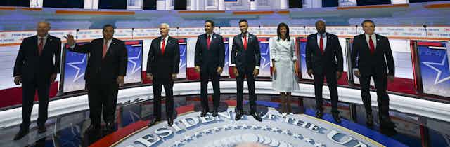 Eight people in business dress stand on a stage.