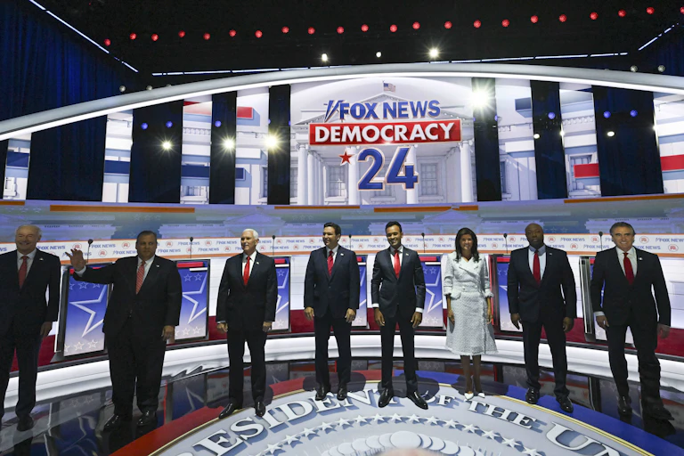 Eight people in business dress stand on a stage.