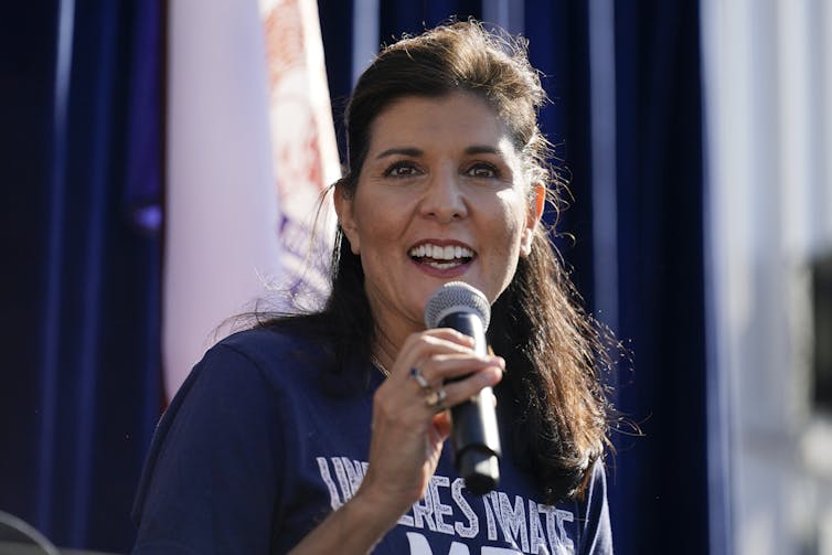 A woman smiles while holding a microphone.
