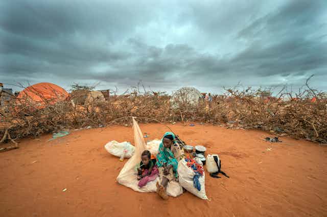 A Somali woman and child wait to be given a spot to settle at a camp for displaced people on the outskirts of Dollow, Somalia