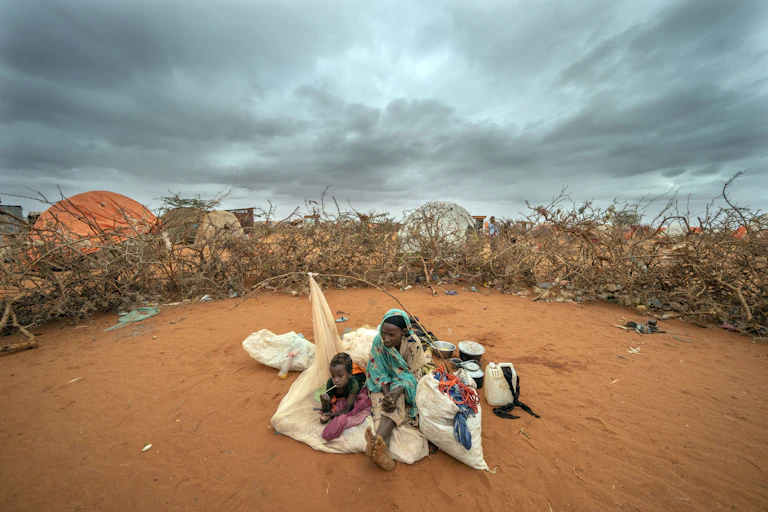 A Somali woman and child wait to be given a spot to settle at a camp for displaced people on the outskirts of Dollow, Somalia