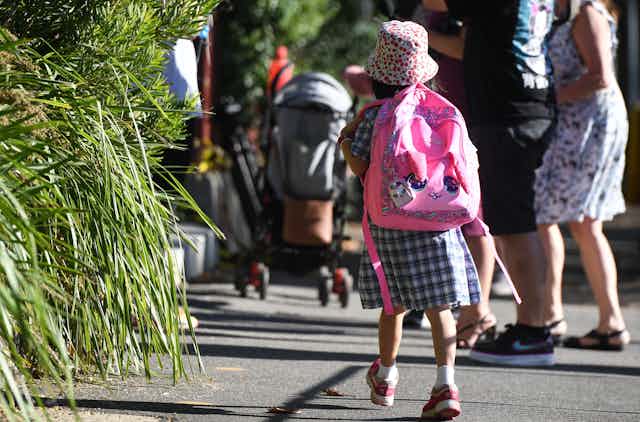 A young student with a huge backpack walks to school. 