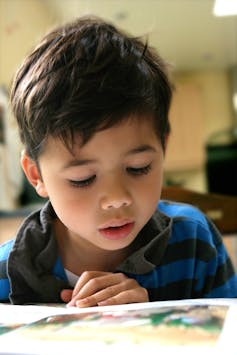 A young boy reads a picture book.