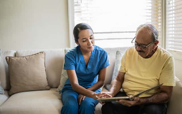 Aged care worker looks at the photo album of an aged resident