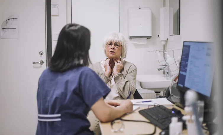 Patient describes her symptoms to a nurse at a desk
