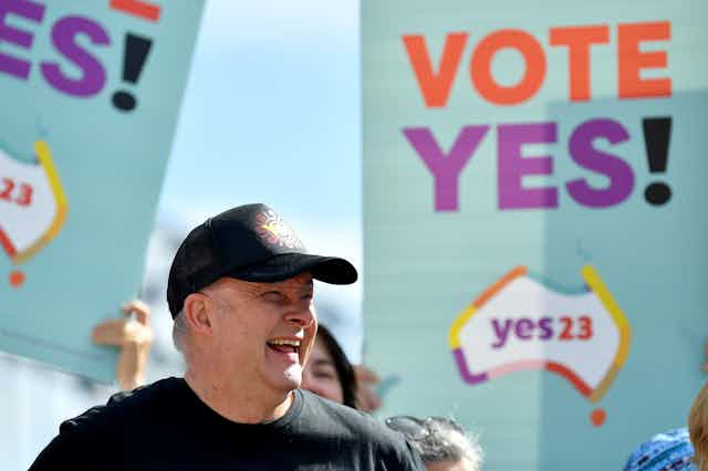 Anthony Albanese smiling in front of yes banners