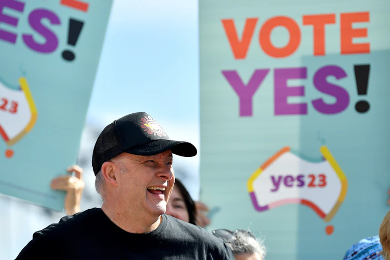 Anthony Albanese smiling in front of yes banners