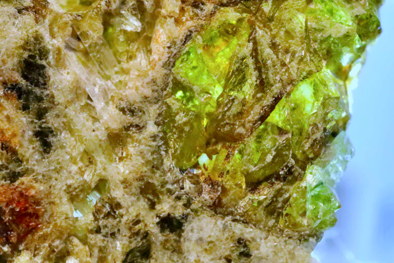 A close up photo of a lump of rock containing green crystals.