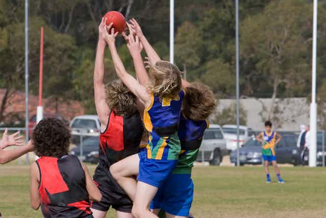 AFL junior players jump for football