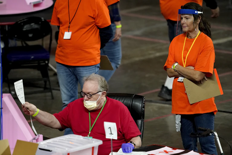 A man holds up a piece of paper while another person views it from behind.