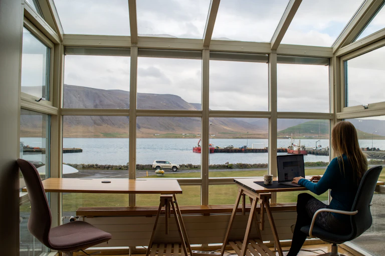 A woman working on her laptop in front of a big window with views.