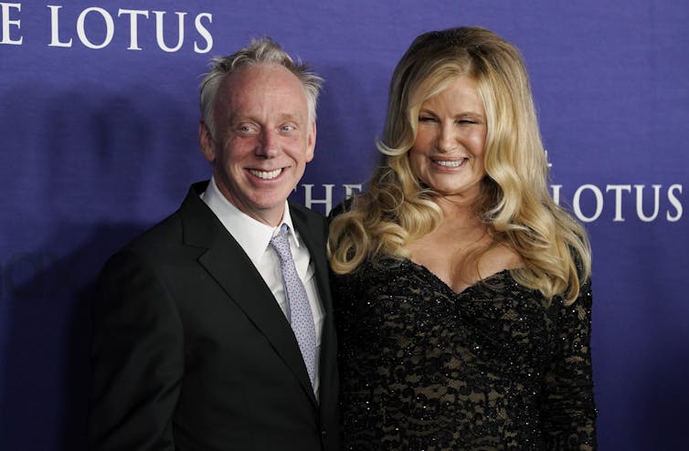A man in suit smiling with woman in black gown.