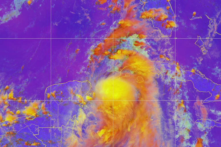A satellite image shows Idalia spilling just west of Cuba with long rain bands.
